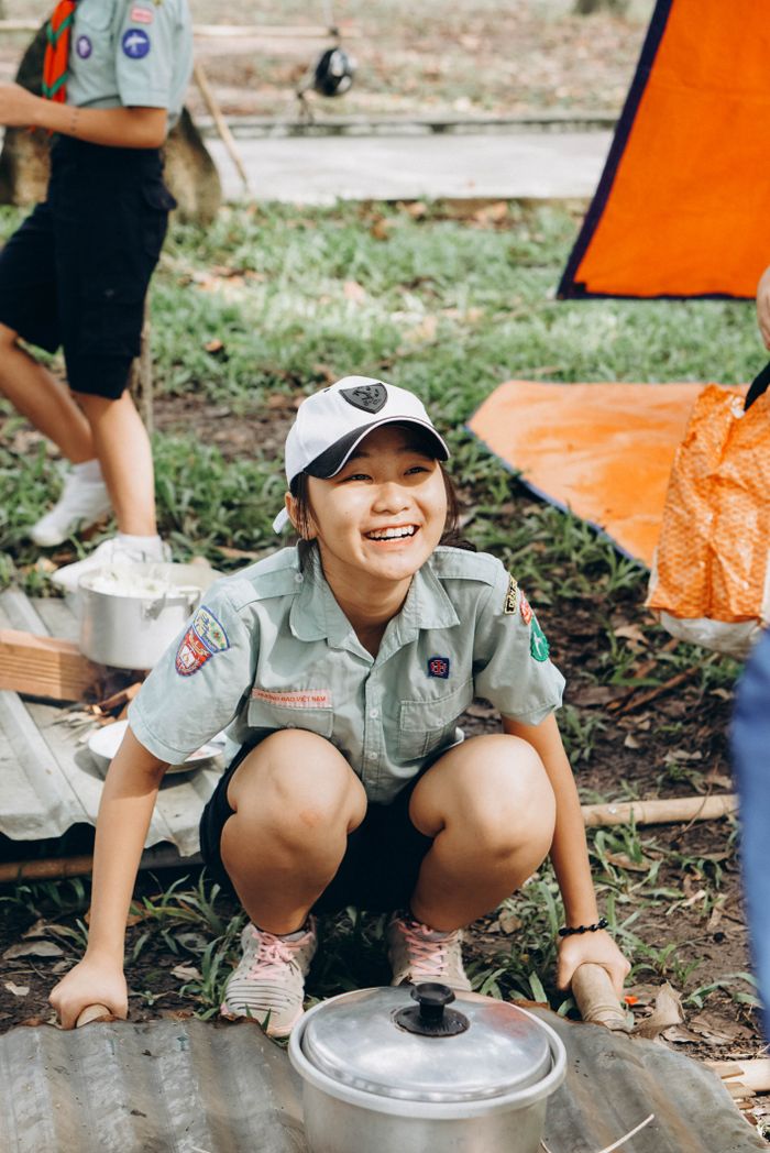 hero-about Smiling scout cooking outdoors during a fun camping activity.