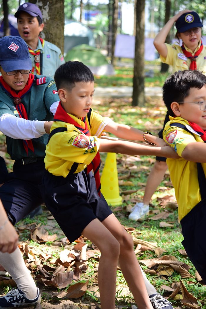 about-02 Young scouts engaged in a tug-of-war challenge outdoors, fostering teamwork.